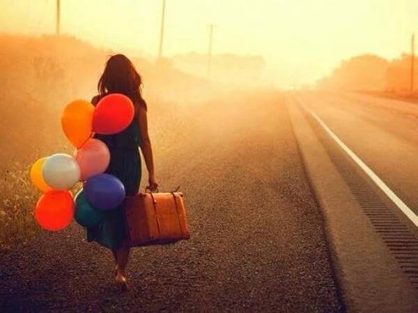ragazza ha paura ma va via con valigia e palloncini colorati