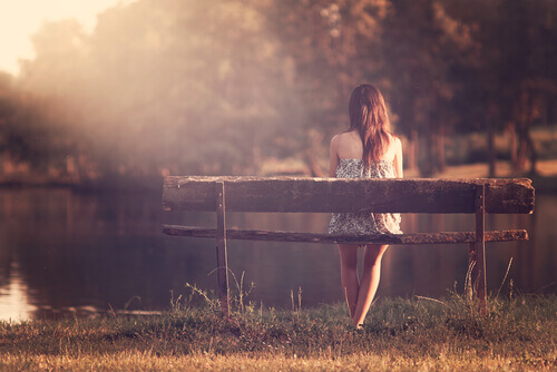 ragazza seduta su una panchina di fronte al lago