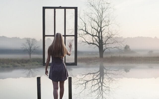 ragazza difronte a lago e finestra sospesa in aria