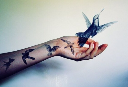 uccelli tatuati sul braccio fuoriescono e volano