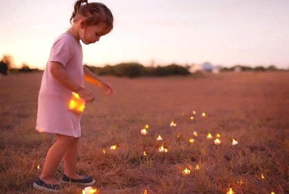 bambina che raccoglie luci in un campo
