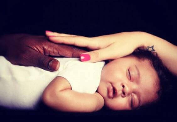 mani di due colori accarezzano bambino