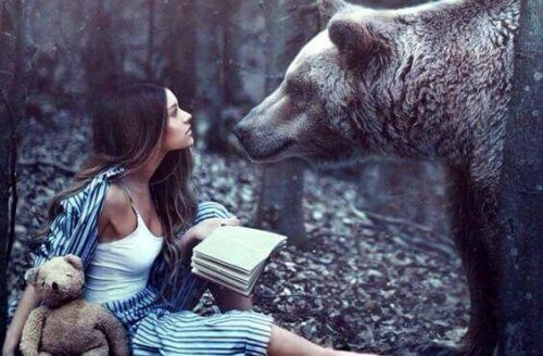 ragazza in mezzo ad un bosco di fronte ad un orso