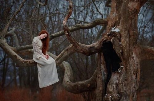 ragazza triste sul ramo di un albero