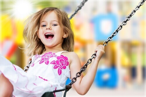 Bambina felice che si dondola in altalena