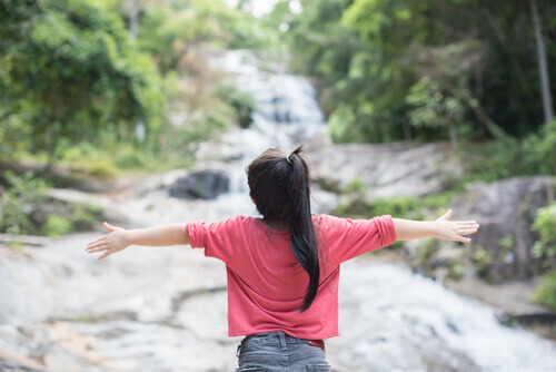 Bambina con le braccia aperte in un bosco