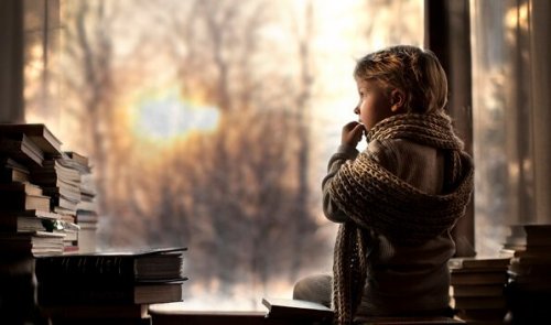 Bambina con sciarpa che guarda fuori dalla finestra
