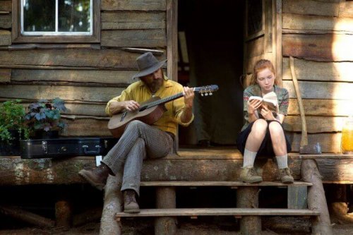 Captain fantastic ragazza che legge e uomo che suona la chitarra