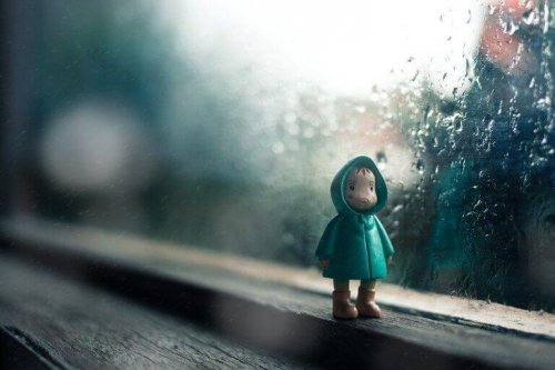 Pupazzetto di bambino davanti ad una finestra mentre fuori piove