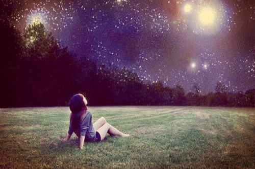 Bambina seduta sull'erba che guarda il cielo e scopre la sua stella