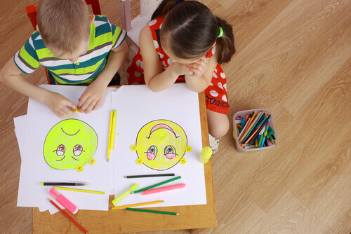 Bambini che disegnano dei volti con varie espressioni ed emozioni, in rappresentazione dell'alfabetizzazione emotiva