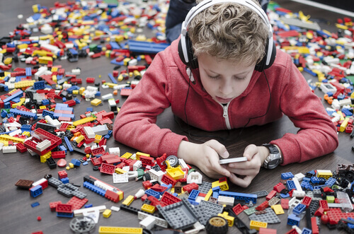 Bambino con lego attorno e smartphone