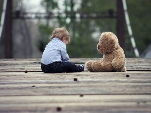 Bambino seduto con il suo orsacchiotto