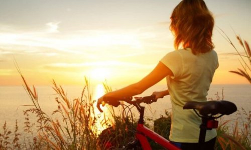 Donna con bicicletta mentre guarda l'alba e si sente motivata