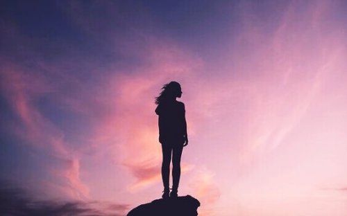 Una donna su una roccia al tramonto