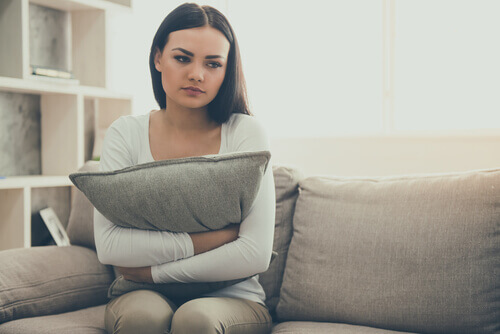 Una ragazza seduta con un cuscino tra le braccia