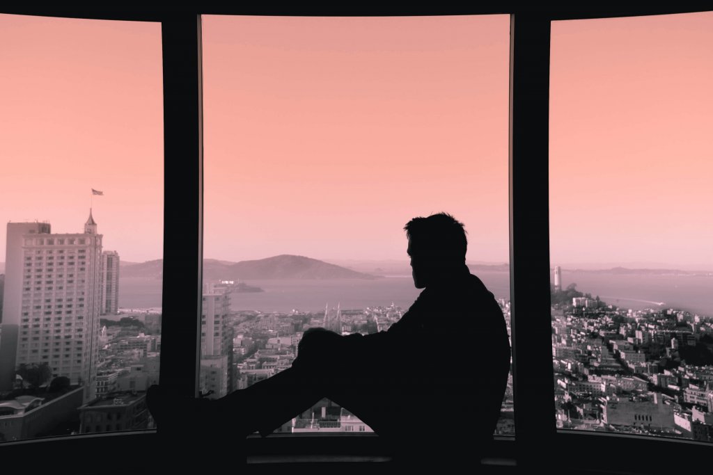 Uomo mentre guarda dalla finestra, pensando al valore di sentire la mancanza di qualcuno