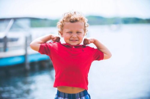 Bambino biondo con le braccia flesse per mostrare i muscoli