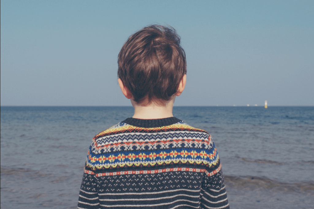 Bambino di spalle che guarda il mare