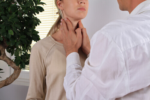 Medico che palpa la tiroide a una paziente
