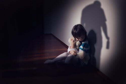 Bambina che abbraccia orsacchiotto per paura dei maltrattamenti.