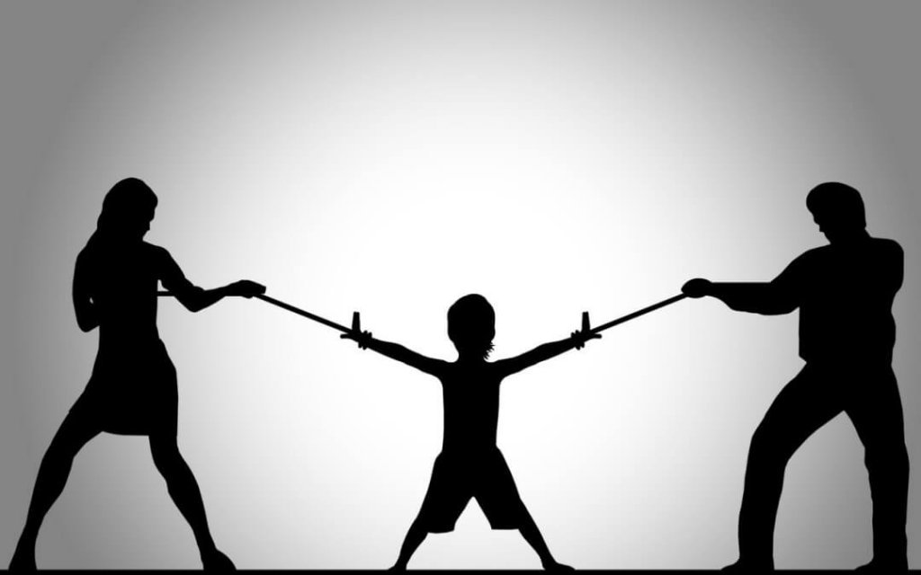 Genitori che tirano le braccia del figlio con una fune