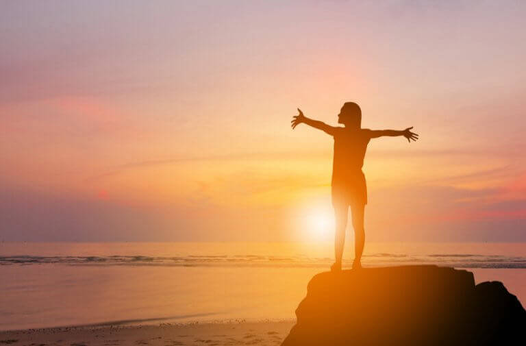Donna con le braccia aperte e tramonto