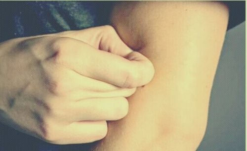 Persona che soffre di disturbo da escoriazione mentre si pizzica un braccio