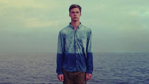 Ragazzo di fronte al mare con camicia bagnata