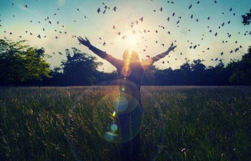 Donna in un campo con degli uccelli che volano