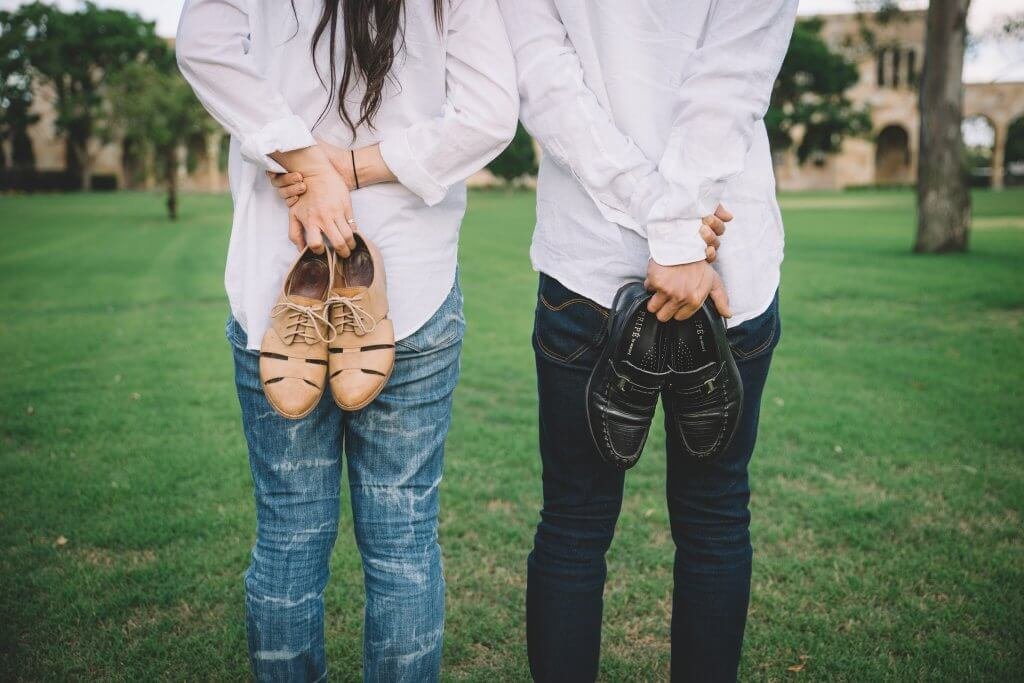Uomo e donna in un campo con le scarpe in mano