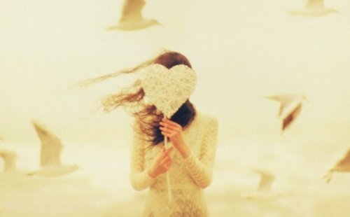 Ragazza che si copre il volto con un cuore