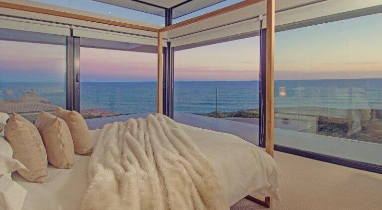 Camera da letto con pareti di vetro e vista sul mare