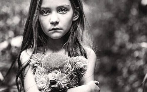 Bambina che stringe un orsetto e rappresenta il dolore cronico infantile