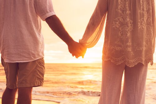 Coppia che si tiene per mano di fronte al mare