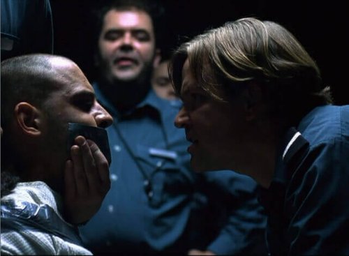 Guardia che tappa la bocca a un prigioniero