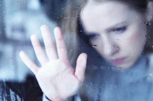 Ragazza dietro alla finestra mentre fuori piove