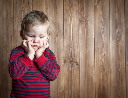 Bambino frustrato con parete in legno dietro