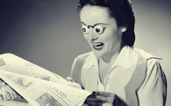 Donna che legge giornale con occhi fuori da orbite