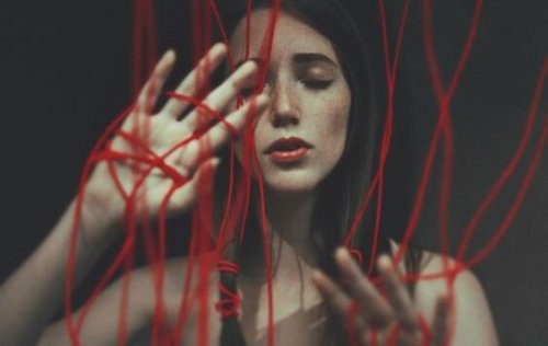 Una donna avvolta da fili rossi