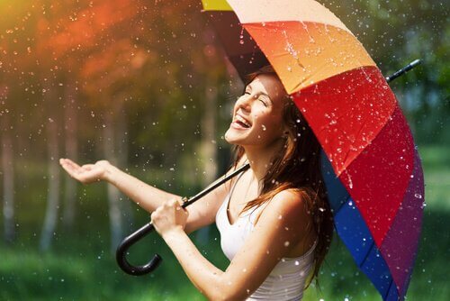 Donna sorridente con ombrello sotto a pioggia essere felici