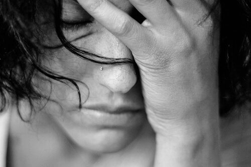 Donna triste che si copre il viso con la mano