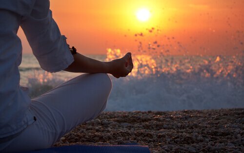 Donna in posizione yoga sulla spiaggia