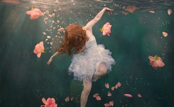 Ragazza sott'acqua circondata da fiori