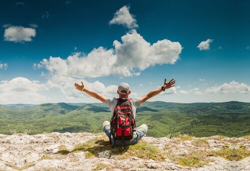 Ragazzo su cima montagna con braccia al cielo