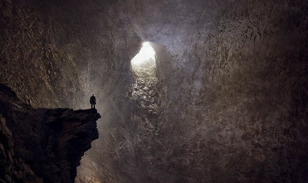 Uomo dentro grotta che guarda via d'uscita