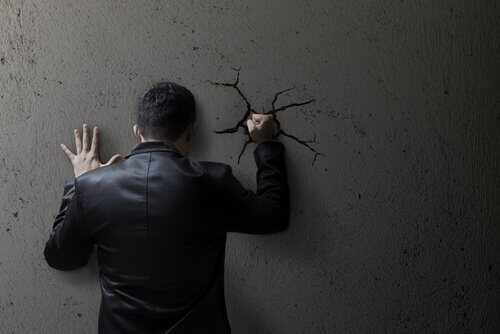 Uomo autodistruttivo che dà un pugno al muro