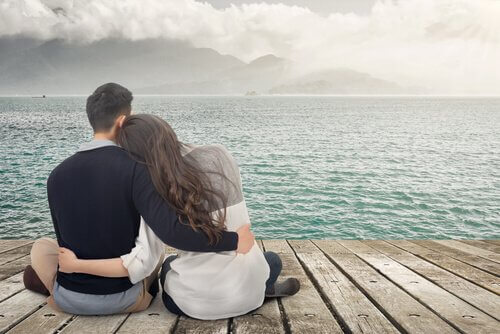 Coppia abbracciata su molo di fronte al mare