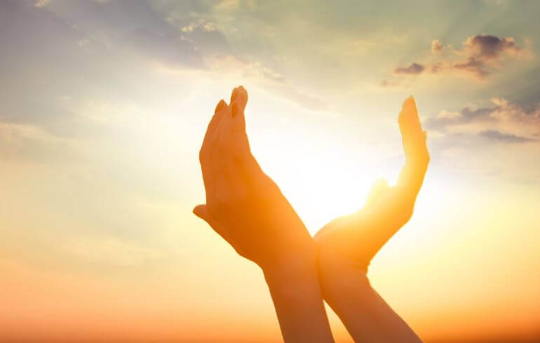 Mani di donna contro luce del sole a simboleggiare spiritualità