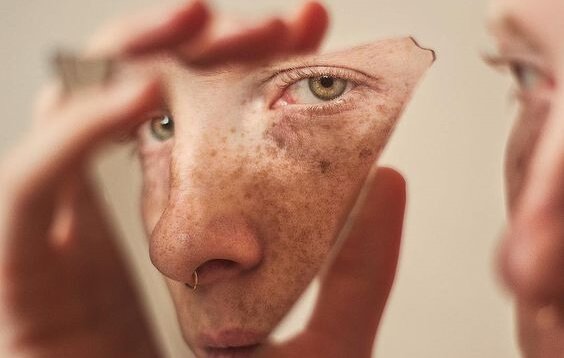 Ragazzo che si guarda in frammento di specchio